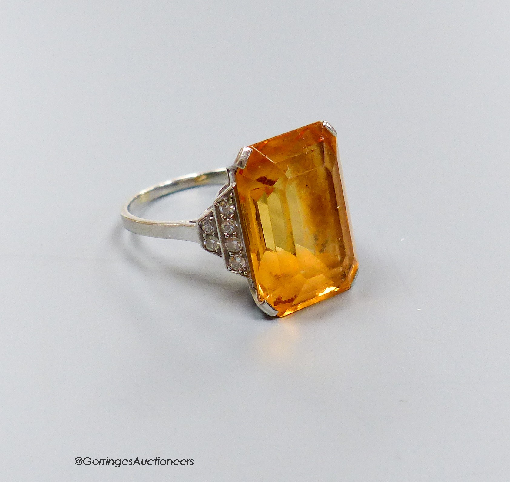 A white metal and emerald cut yellow topaz set dress ring, with diamond set shoulders, size N, gross weight 6.5 grams.